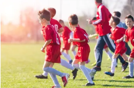 Youth soccer team huddled on the field, representing liability insurance coverage for amateur sports leagues and programs.